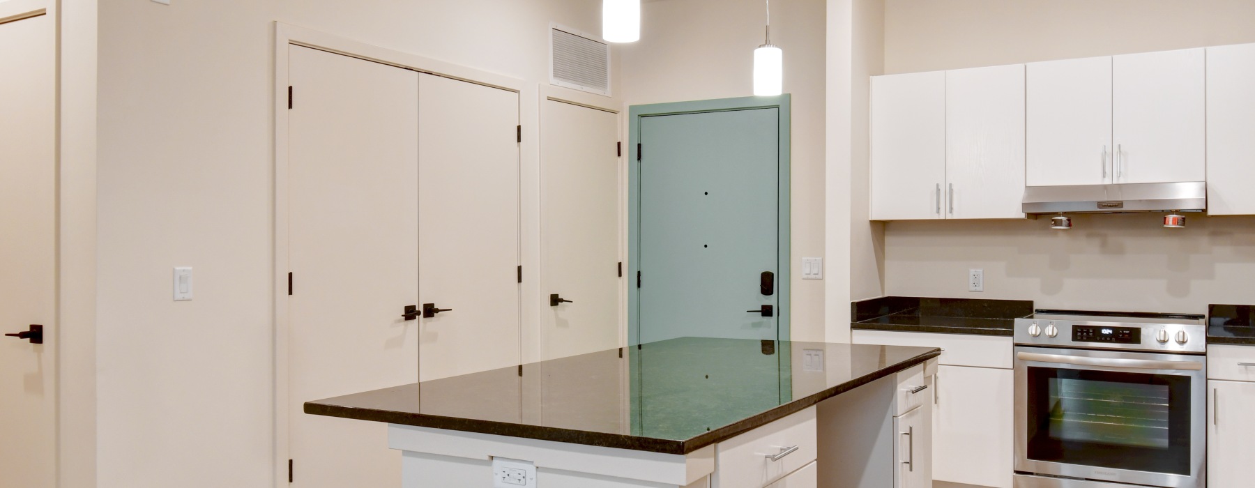 Apartment kitchen with white walls and green entryway door